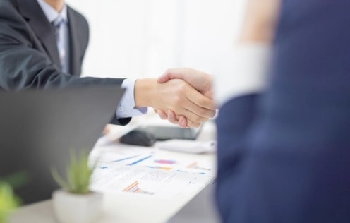 スーツ姿の男性二人が握手している手のアップの写真